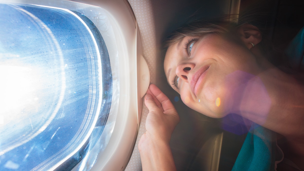 Donna che guarda dall'oblò in aereo: A cosa serve e come funziona l’ESTA obbligatorio