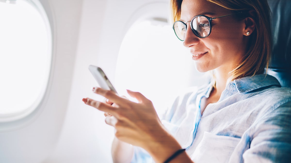 donna usa smartphone in aereo
