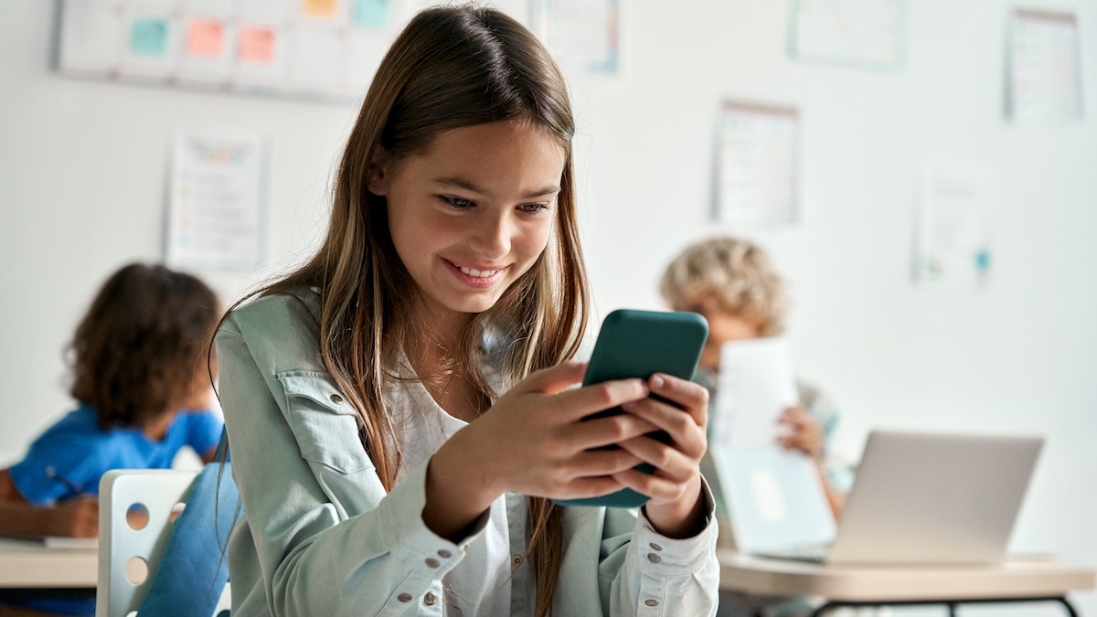 Bambina scuola con un cellulare in mano