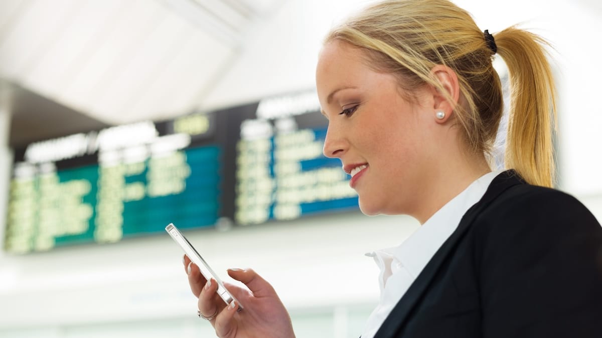 Donna con telefono in mano alla stazione