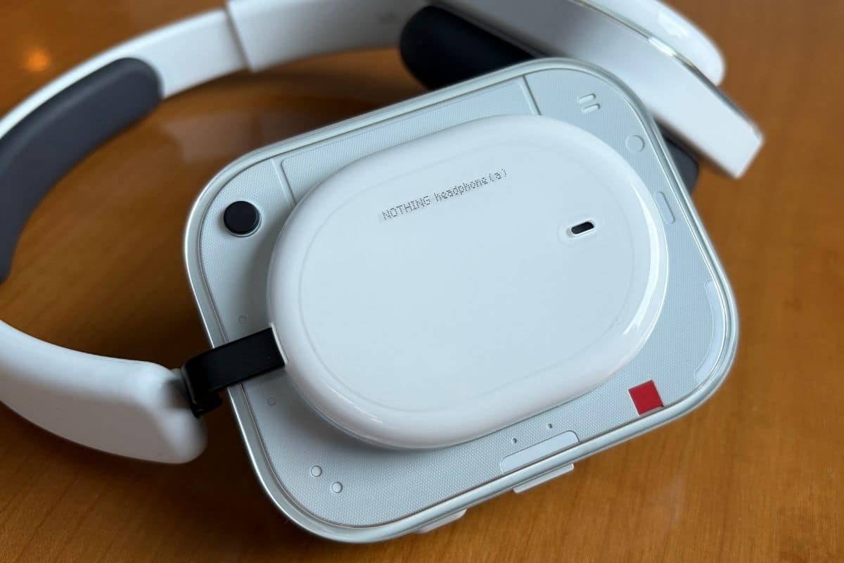 La cover esterna di Nothing Headphone (a) White in primo piano: il design semi-trasparente lascia intravedere la struttura interna, con il caratteristico accento rosso che firma l'identità Nothing. (mistergadget.tech)