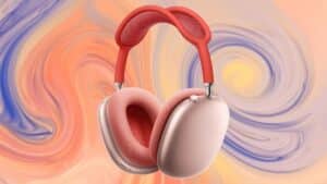 Un paio di AirPods Max in finitura rosa con archetto rosso è mostrato su uno sfondo astratto dai toni pastello.