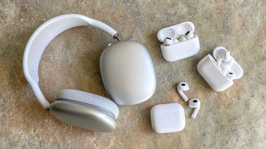 Un paio di AirPods Max argentate è affiancato da diversi modelli di AirPods e relative custodie di ricarica su una superficie chiara.