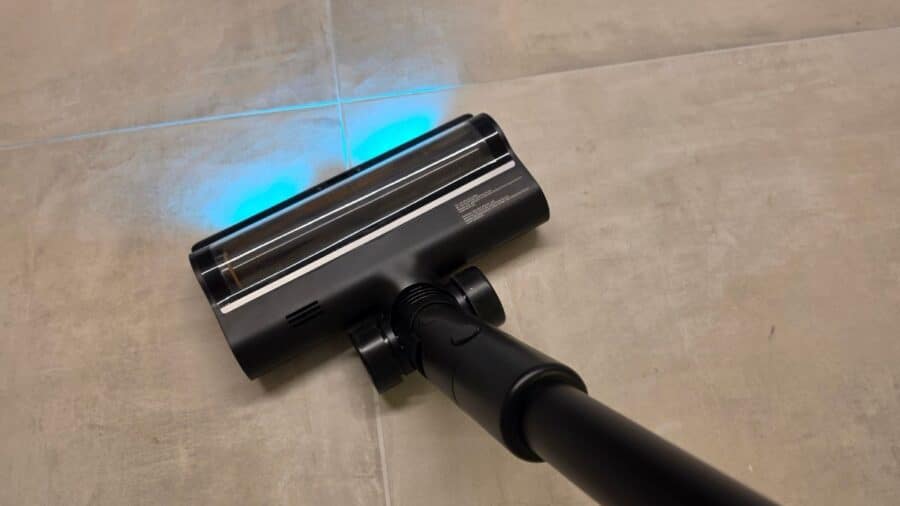 Testina aspirapolvere brushless nera del Dreame H15 Mix su pavimento in gres, con illuminazione LED azzurra anteriore del sistema di rilevamento sporco CelesTect