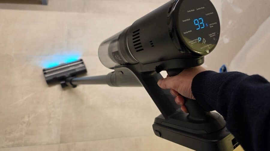 Mano che impugna il modulo motore cilindrico nero del Dreame H15 Mix, con display rotondo che mostra il livello batteria al 93% e le modalità operative, testina con luce blu in primo piano