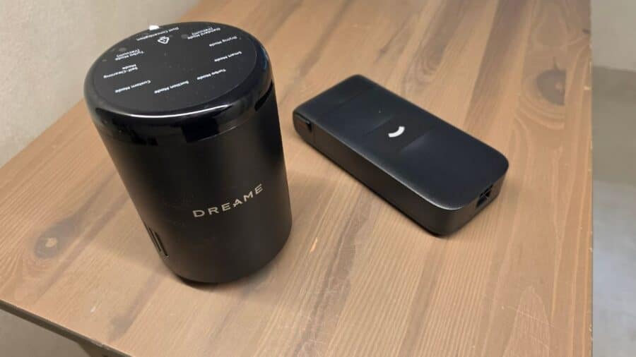 Modulo motore cilindrico nero Dreame con etichetta del brand affiancato dalla batteria rimovibile nera rettangolare, entrambi poggiati su un piano in legno