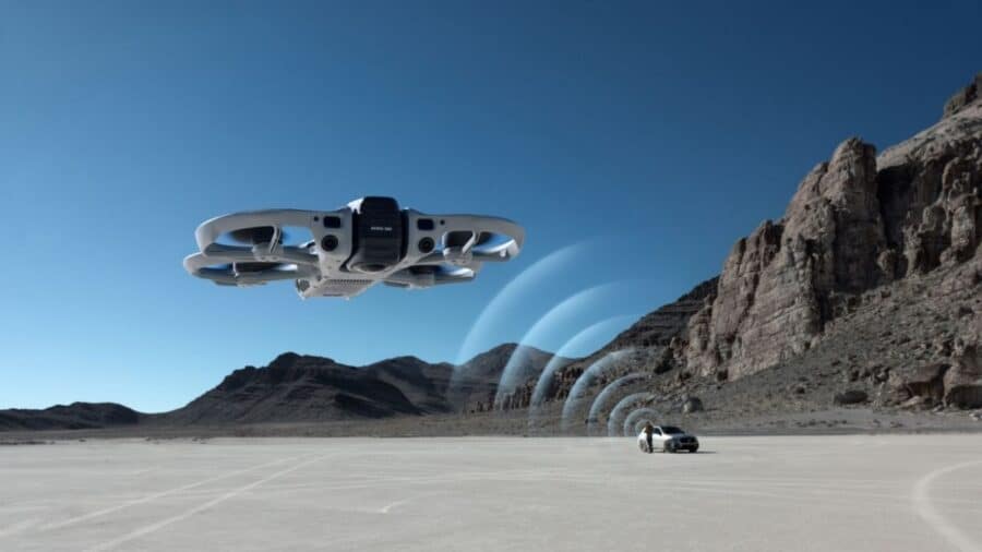 DJI Avata 360 in volo su un deserto roccioso con grafica del sistema di rilevamento ostacoli omnidirezionale attivo e un'auto sullo sfondo
