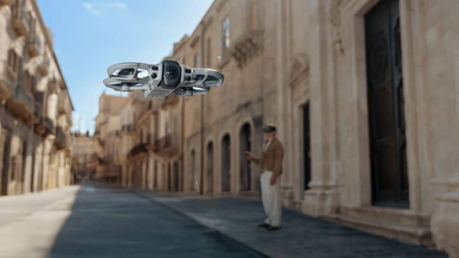 DJI Avata 360 in volo in un centro storico con architettura barocca e pilota con goggles sullo sfondo