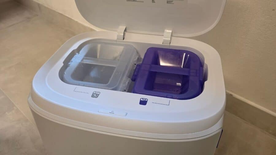 Interno della base Narwal Freo Z10 Pro con coperchio aperto, serbatoio trasparente a sinistra e viola a destra