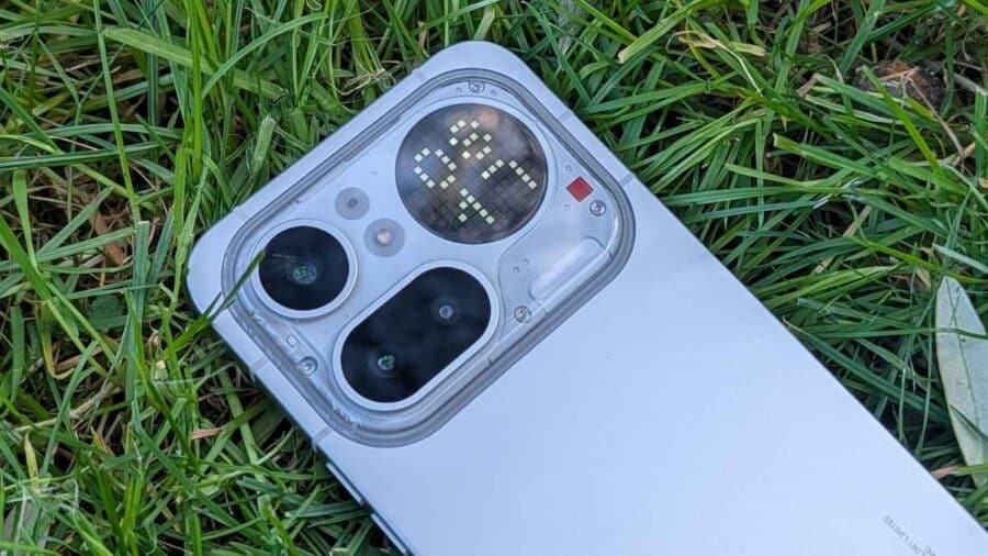 Dettaglio del modulo fotocamera del Nothing Phone (4a) Pro sull'erba, con bumper trasparente e Glyph Matrix acceso con caratteri luminosi