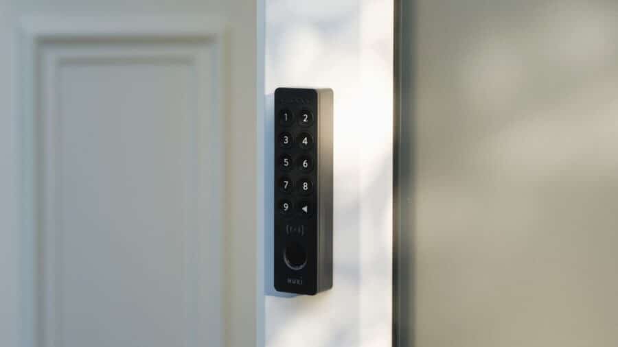 Mano che avvicina uno smartphone al Nuki Keypad 2 NFC per aprire la porta con Tap to Unlock