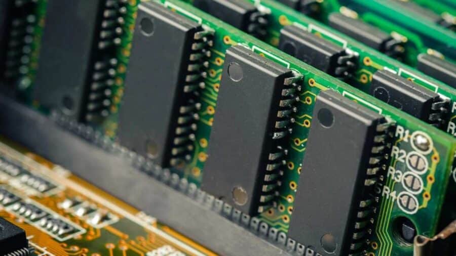 Primo piano di diversi moduli di memoria RAM montati su una scheda elettronica, con chip neri allineati su circuiti verdi.