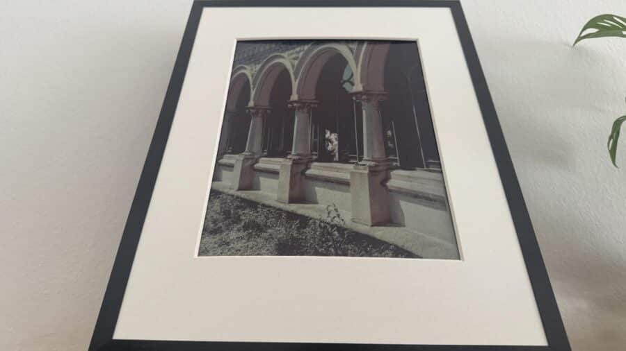 Primo piano frontale dello SwitchBot AI Art Frame con una fotografia di un chiostro con colonne e archi.