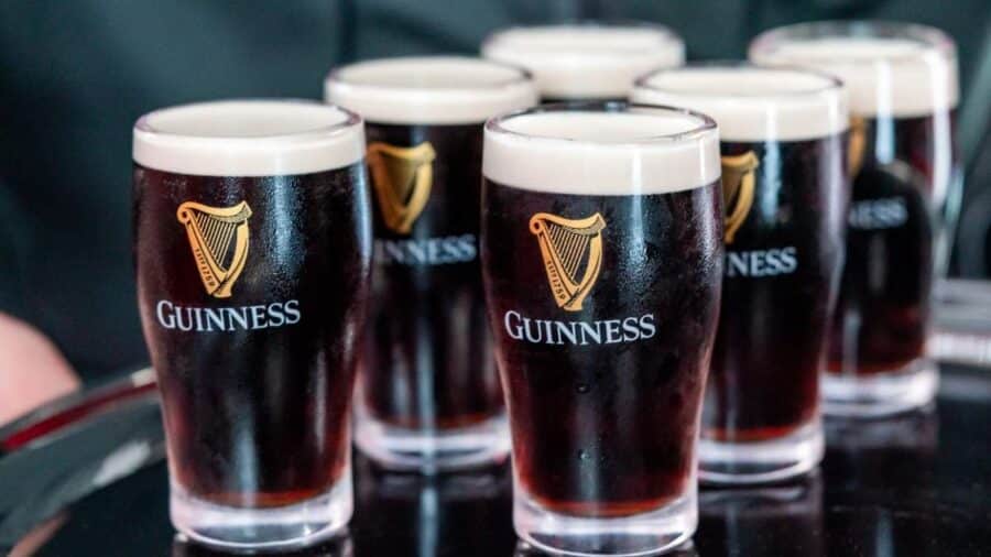 Diversi bicchieri di Guinness appena serviti sono disposti su un vassoio, con la tipica schiuma chiara in superficie.