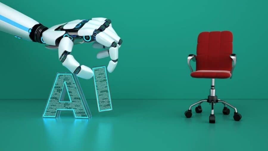 Una mano robotica solleva la scritta luminosa “AI” accanto a una sedia da ufficio rossa su sfondo verde.