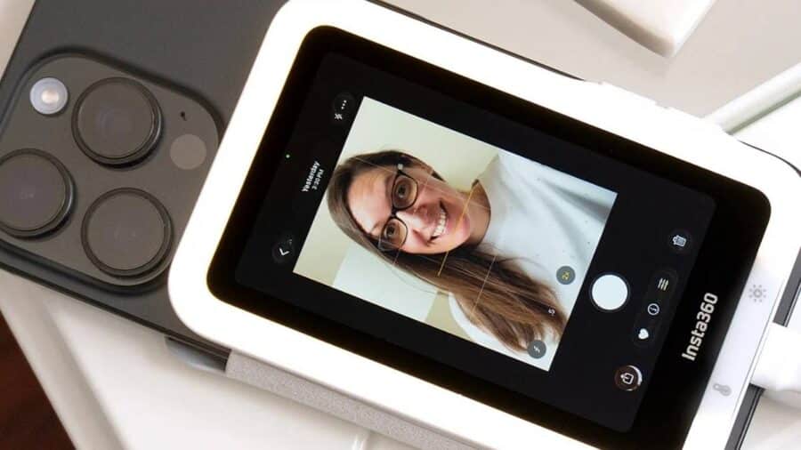 Primo piano di Insta360 Snap collegato a uno smartphone, con il piccolo display che mostra una persona inquadrata in modalità selfie.