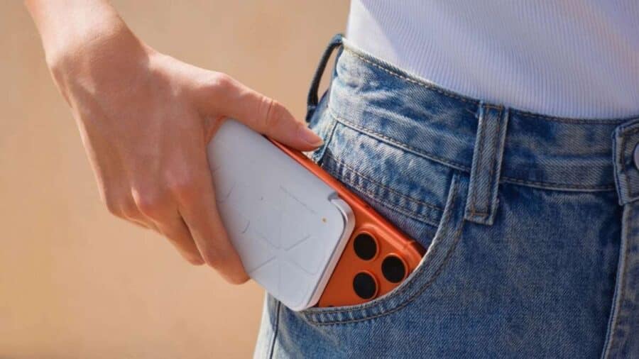 Una mano inserisce uno smartphone con Insta360 Snap ripiegato nella tasca dei jeans, mostrando il design compatto dell’accessorio.