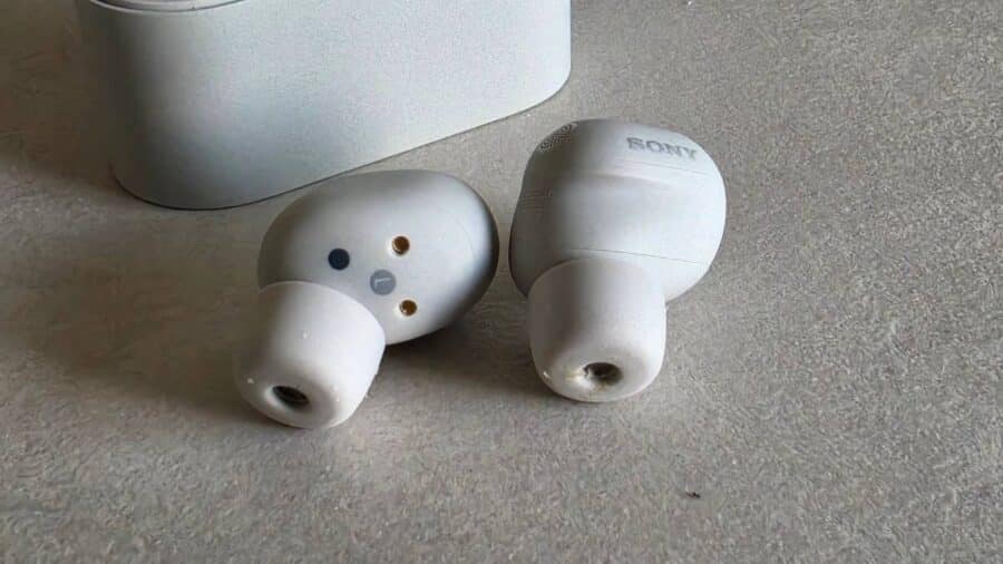 Sony WF-1000XM6 coppia di auricolari con i pin di ricarica visibili, custodia sullo sfondo
