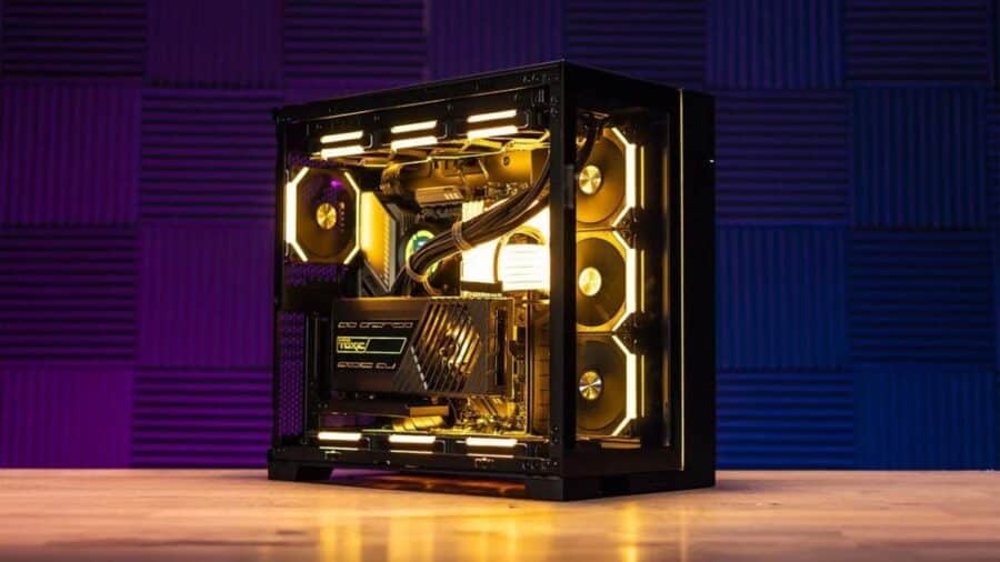 Un PC desktop con pannello laterale in vetro mostra componenti interni illuminati da luci RGB gialle, tra ventole, dissipatore e scheda video.