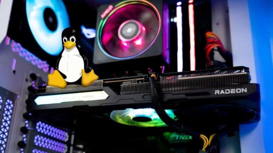Mascotte Tux appoggiata sopra una scheda video AMD Radeon montata in un case da gaming, con ventole RGB e componenti illuminati sullo sfondo.