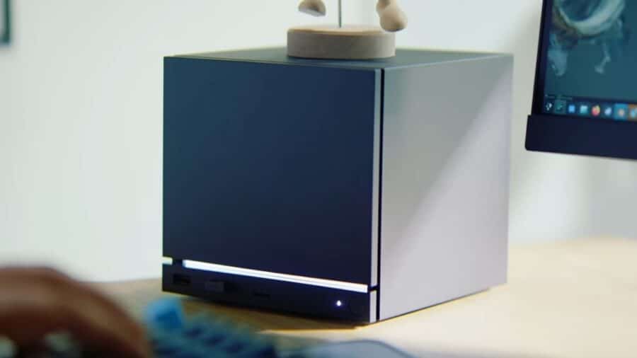 Mini PC o desktop compatto dal design minimalista, con pannello frontale pulito e piccola striscia luminosa, posizionato su una scrivania accanto a un monitor.