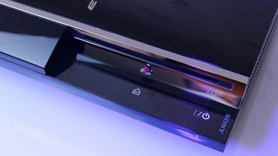 Dettaglio ravvicinato del frontale di una PlayStation 3 con lettore Blu-ray slot-in, logo PlayStation centrale e tasto di accensione illuminato.