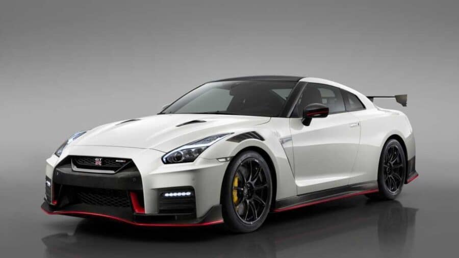 Nissan GT-R Nismo bianca fotografata in studio, con dettagli aerodinamici neri e profili rossi sul frontale e sulle minigonne.