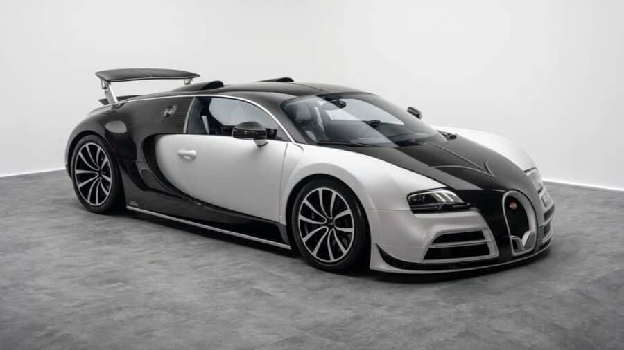 Bugatti Veyron bicolore bianca e nera in studio, vista di tre quarti anteriore con carrozzeria larga e dettagli in fibra di carbonio.