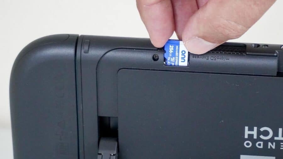 Una mano inserisce una scheda microSD Express nello slot posteriore di Nintendo Switch 2.