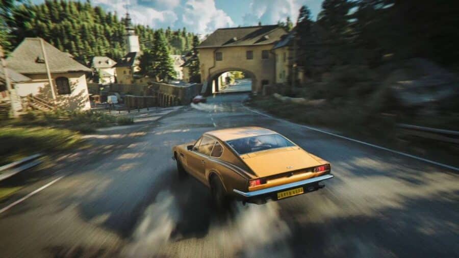 Auto sportiva color oro sfreccia ad alta velocità su una strada di campagna attraversando un piccolo borgo, con forte effetto motion blur e atmosfera cinematografica.