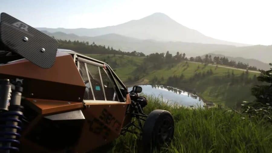 Un buggy arancione fermo sull’erba accanto a un lago, con colline verdi e una montagna sullo sfondo nel mondo di gioco di Forza Horizon 6 ambientato in Giappone.