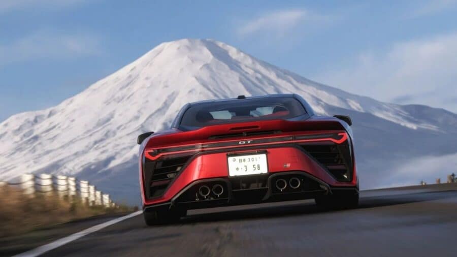 Supercar rossa ripresa da dietro mentre corre su una strada di montagna con il Monte Fuji innevato sullo sfondo.