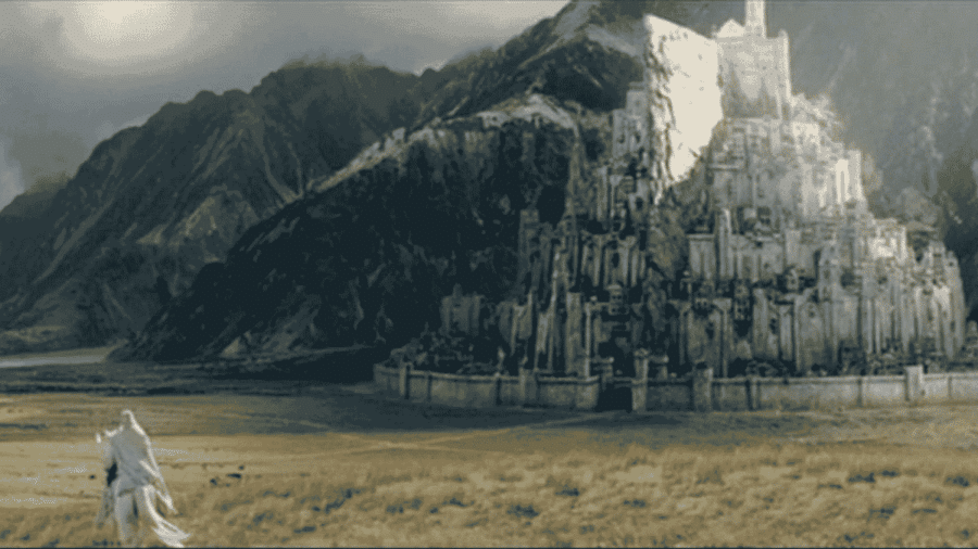 Paesaggio fantasy della Terra di Mezzo con una grande città bianca ai piedi delle montagne e una figura incappucciata in lontananza.