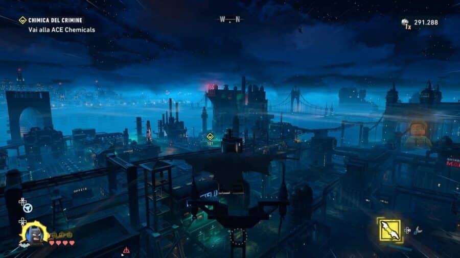 Batman plana sopra Gotham City in LEGO Batman L’Eredità del Cavaliere Oscuro, con skyline notturno, grattacieli industriali e missione attiva verso ACE Chemicals.