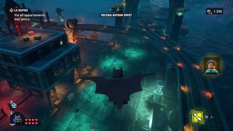 Batman vola sopra Vecchia Gotham Ovest in LEGO Batman L’Eredità del Cavaliere Oscuro, sorvolando strade, tetti e binari sopraelevati illuminati di notte.