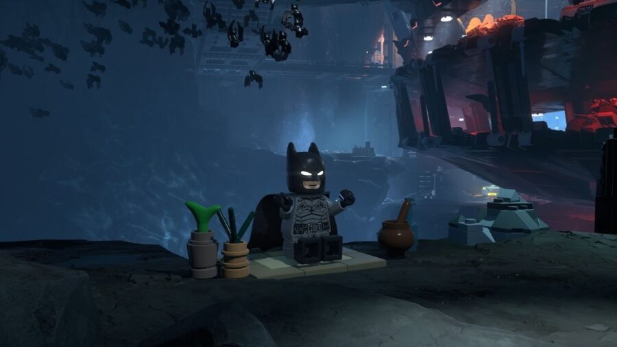 Batman in versione LEGO seduto in una caverna con pipistrelli sullo sfondo, circondato da piccoli oggetti e ambientazioni sotterranee.