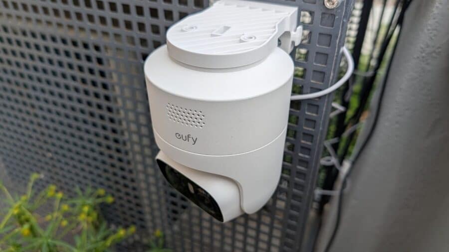 eufyCam C37 installata su staffa a parete con supporto pannello solare superiore, vista laterale su sfondo verde esterno