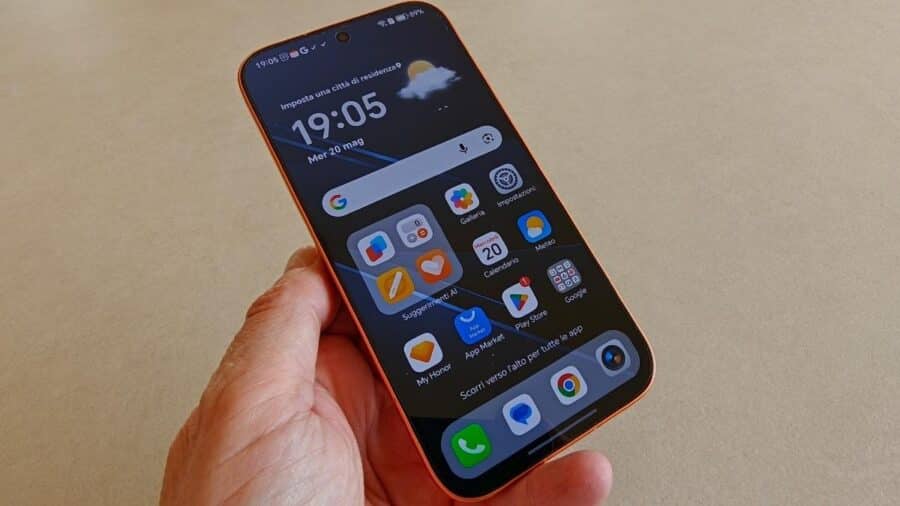 Honor 600 arancione tenuto in mano con display acceso che mostra la schermata principale di MagicOS 10