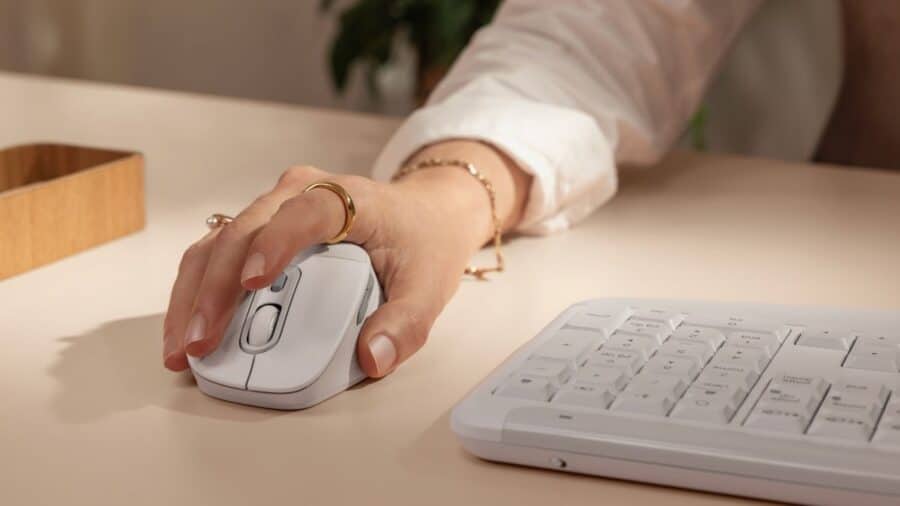 Dettaglio mano sul mouse Logitech M840 L in colorazione bianca con tastiera MK880 sullo sfondo