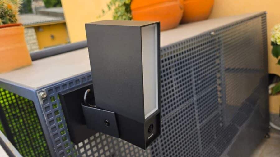 Netatmo Videocamera Esterna Original vista dal lato sinistro, montata su staffa a parete con ringhiera sullo sfondo