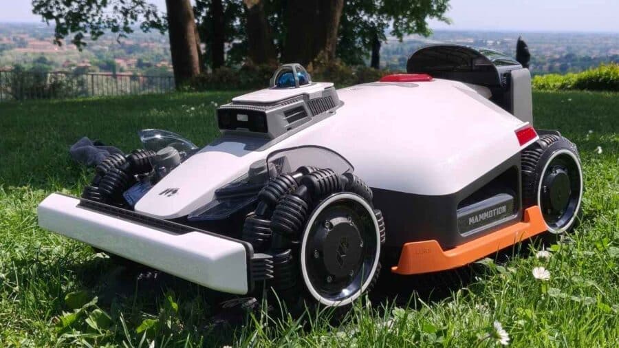Mammotion Luba 3 AWD 3000 ripreso di tre quarti sul prato, visibili la doppia telecamera AI, il LiDAR e le protezioni laterali removibili arancioni