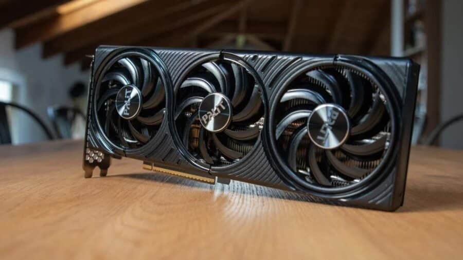 Scheda video Palit NVIDIA GeForce RTX 5060 Ti con tre ventole, appoggiata su un tavolo in legno.