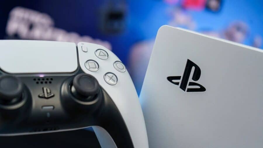 Primo piano di un controller DualSense accanto alla scocca bianca di una console PlayStation, con il logo Sony ben visibile e sfondo sfocato in tonalità blu.