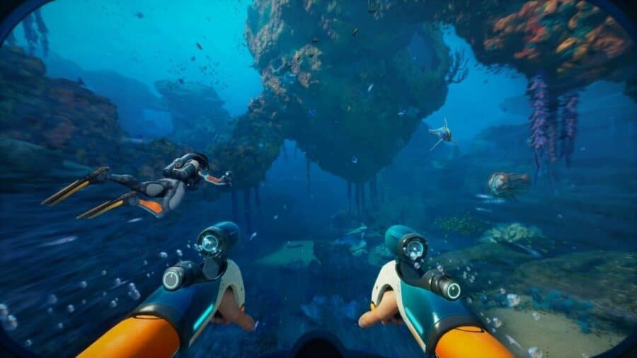 Visuale in prima persona sott’acqua con due propulsori impugnati, un sub che nuota davanti e grandi formazioni rocciose sommerse popolate da creature marine.