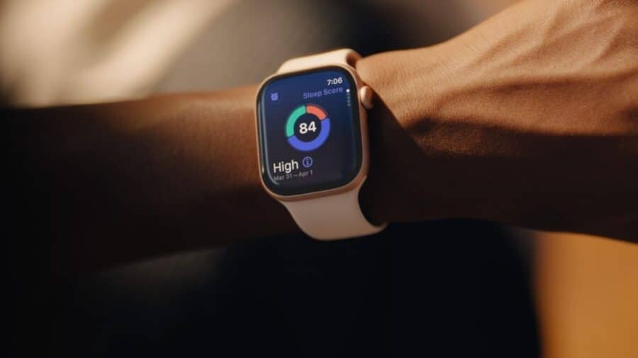 Apple Watch al polso di una persona mentre mostra sul display un punteggio del sonno con grafico circolare colorato.