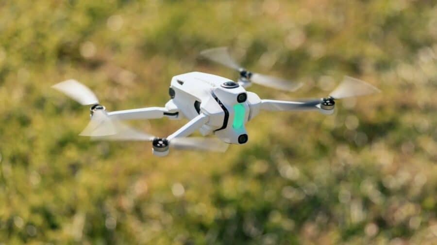Drone Antigravity A1 bianco in volo sopra un prato, con eliche in movimento e sfondo naturale sfocato.
