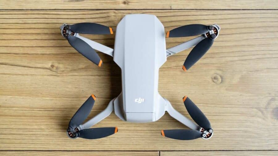 DJI Mini 4K visto dall’alto su una superficie in legno, con bracci aperti ed eliche nere.