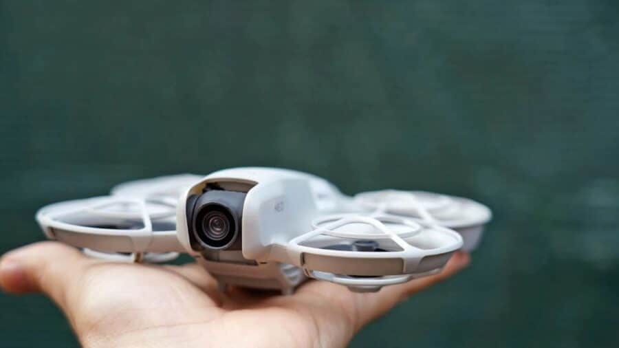 DJI Neo appoggiato sul palmo di una mano, con fotocamera frontale e paraeliche integrati.