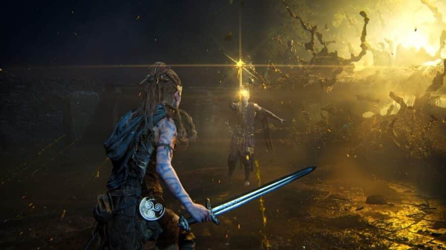 Senua impugna una spada davanti a un nemico avvolto da energia dorata, durante una sequenza di combattimento in un ambiente oscuro.
