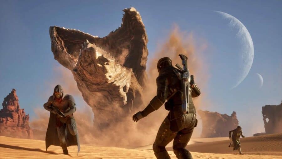 Personaggi in armatura affrontano una gigantesca creatura nel deserto di Dune Awakening, con lune e paesaggio sabbioso sullo sfondo.